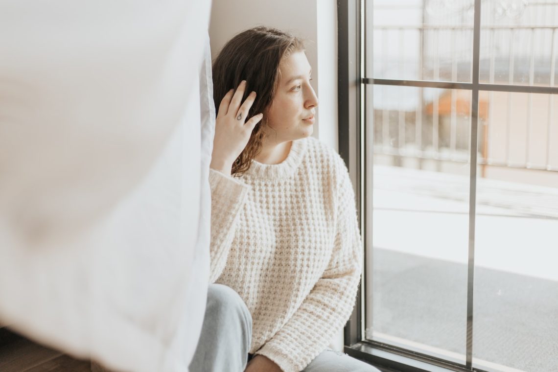 woman in white and gray long sleeve shirt covering her face by white textile